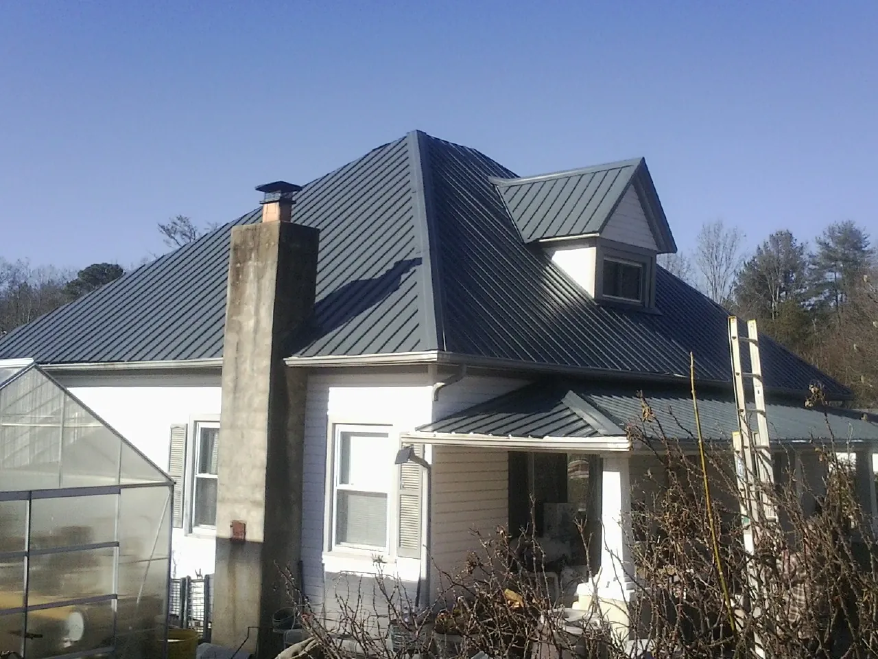 Dark blue standing seam metal roof on a white farmhouse with dormer — Slate & Tile Roof Repair by Roofing Brothers in North Manchester