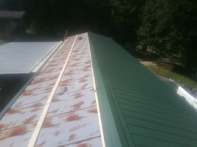 Old rusted panels beside newly installed green metal roofing — Wind Damage Roof Repair by Roofing Brothers in North Manchester
