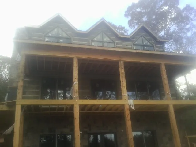 Dormers and porch framing on a large log home under construction — Roof Coating work by our crew in North Manchester