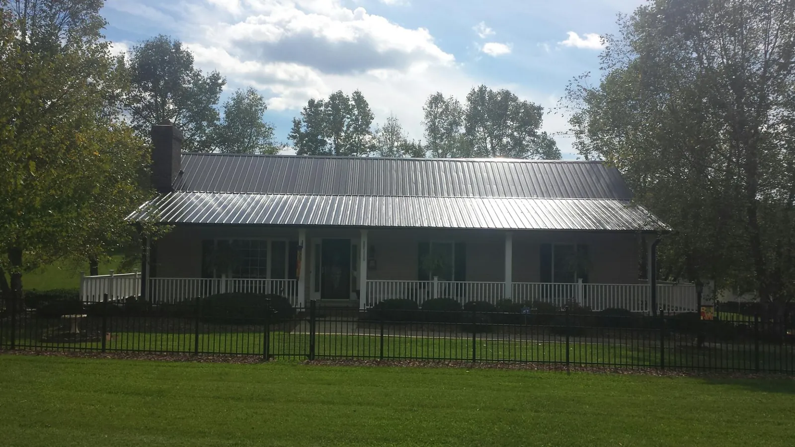 Gray metal roof on a brick ranch with a full width front porch — Gutter Guard Installation work by our crew in North Manchester
