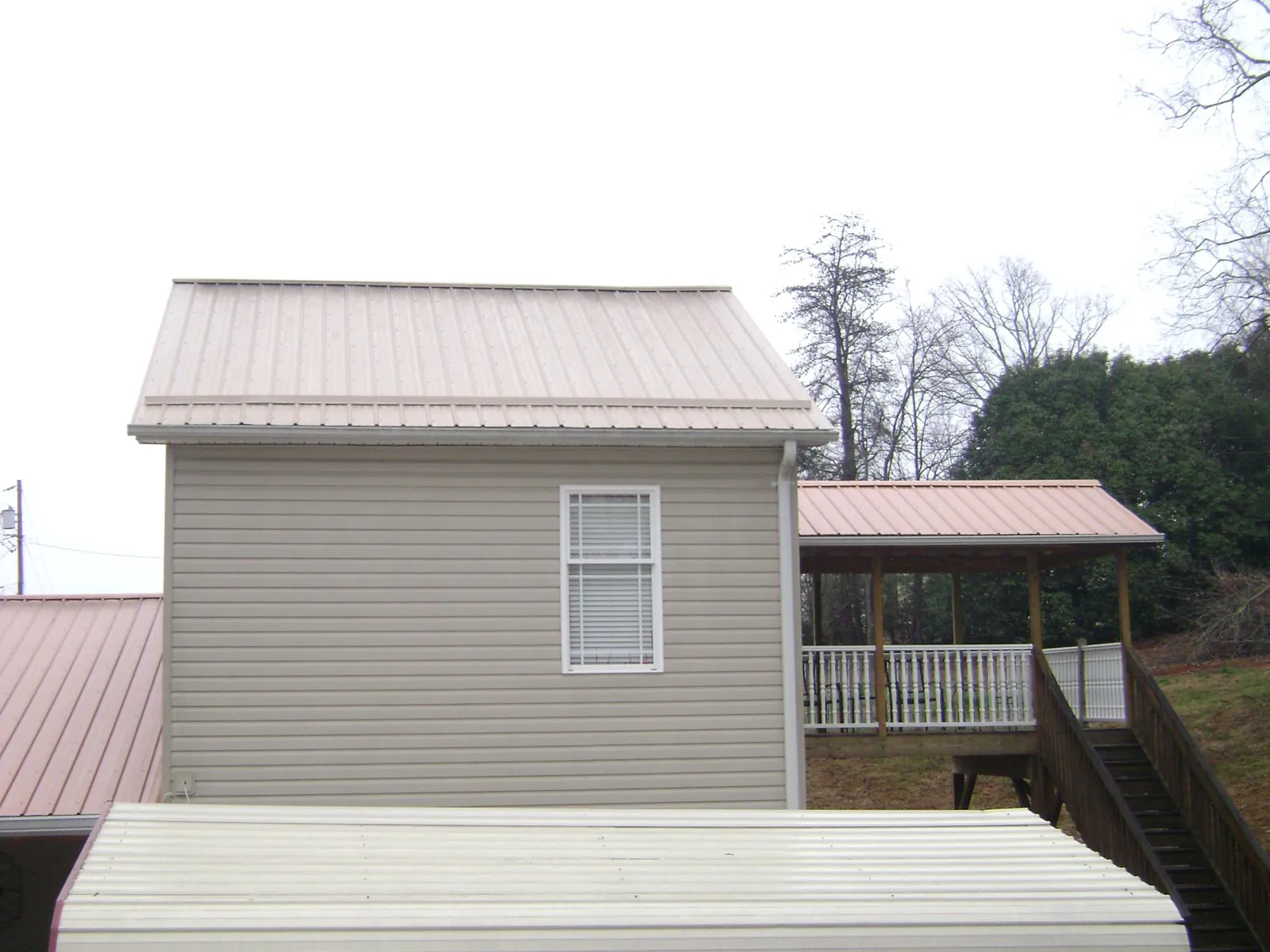 Tan metal roofs on a two story addition and attached porch, from a Roof Replacement job in North Manchester
