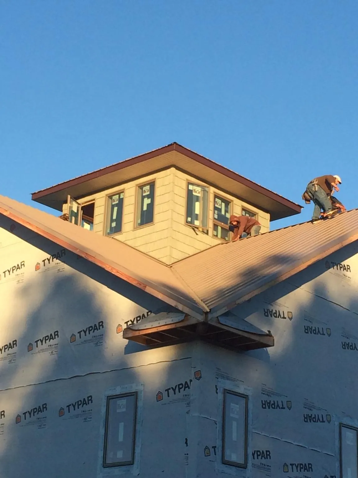 Roofers working around a rooftop cupola on a new metal roof at sunset — Roof Waterproofing in North Manchester by Roofing Brothers
